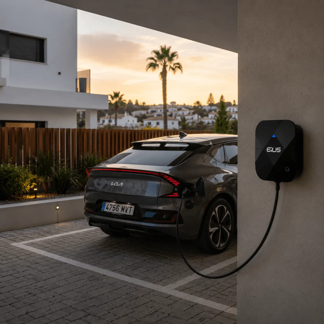 KUBIC 74M wallbox mounted on a garage wall charging an electric car at dusk